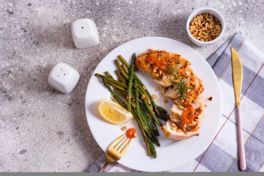 Izgara tavuk göğsü ızgara kuşkonmaz ve koyu taştan arka planda limon dilimi. Paleo diyeti.