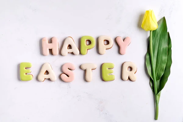 Feliz Pascua, Letras de galletas y tulipán amarillo sobre fondo de mármol . — Foto de Stock