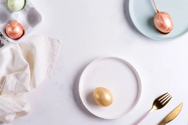 Oster-Tischdecken von oben. Eleganter leerer Teller, Besteck, Serviette und goldene Eier auf Stein — Stockfoto