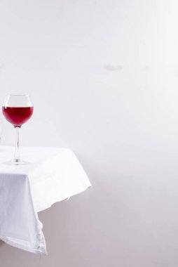 Beyaz tekstil arka planında gölgeli şarap kadehinde kırmızı şarap.