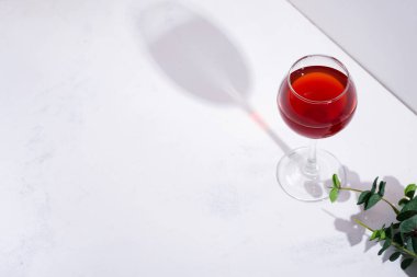 Şarap kadehinde kırmızı şarap. Arka planda gölgeler var.