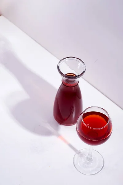 Vörösbor borosüvegben és borosüvegben, fehér kő alapon elszigetelt árnyékokkal — Stock Fotó