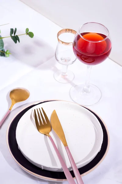 Geschirr und Dekorationen zum Servieren einer festlichen Tafel. Teller, Rotweinglas und Besteck auf weißem Textilhintergrund. — Stockfoto