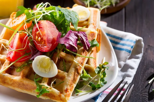 Close up view of freshly cooked healthy breakfast with homemade waffles, tomatoes and cut egg on a plate on a wooden background. — 스톡 사진