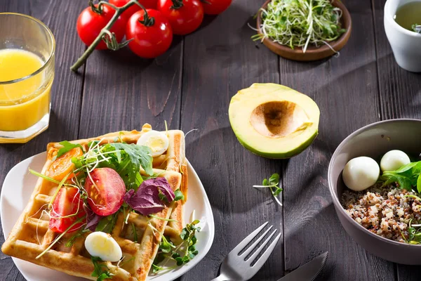 Morning healthy breakfast with vegetables salad on homemade waffles, greenery and cut avocado on a wooden background. — 스톡 사진