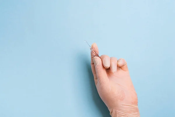 Womans hands in the medical gloves holds vaccine ampoule on a light blue background. — ストック写真