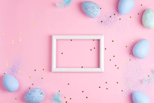 Festive frame with painted eggs of pastel blue colors and confetti decoration on a light pink background. — 图库照片