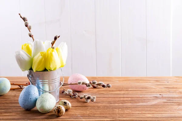 用刚刚采摘的春色郁金香花和手工制作的彩蛋 在浅灰墙上的木制桌子上 仿制球拍 创作出喜庆的作品 — 图库照片