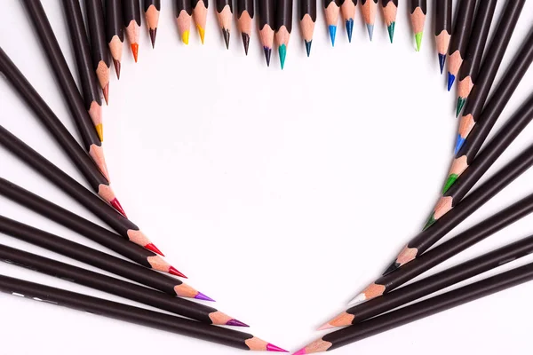 Δημιουργικό σκηνικό από πολύχρωμα μολύβια σε σχήμα καρδιάς σε λευκό φόντο. Επίπεδη. — Φωτογραφία Αρχείου