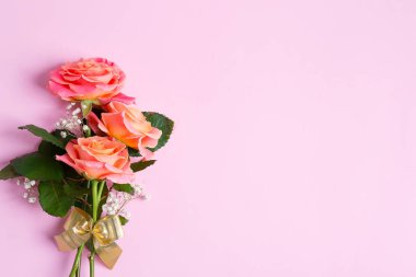 Pastel pembe arka planda taze koparılmış gül buketinden bir tebrik kartı..