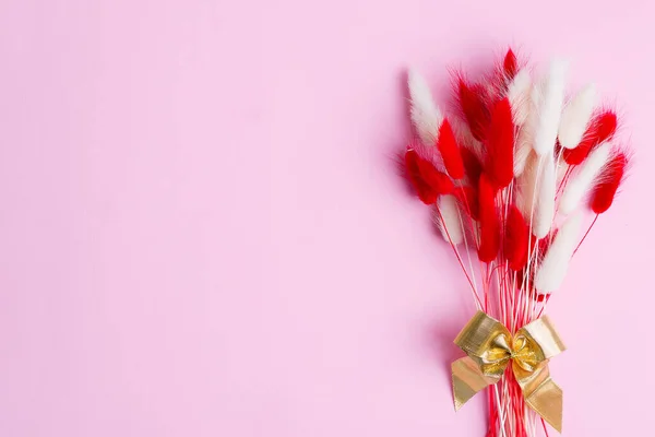Marco de esquina festivo con flores secas suaves de otoño, rojas y blancas, hierba Lagurus Ovatus sobre un fondo rosa . —  Fotos de Stock