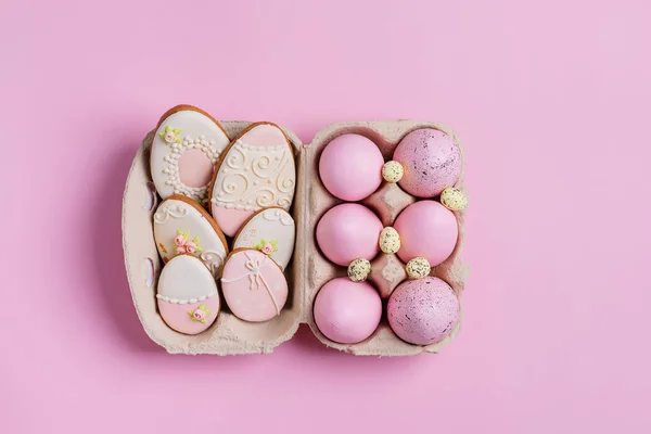 Composición de Pascua a partir de huevos pintados artesanalmente en caja de papel y galletas horneadas sobre un fondo rosa . — Foto de Stock