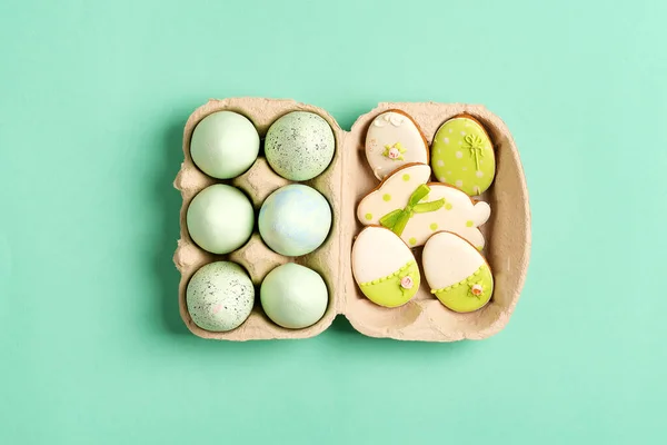Composición de Pascua de huevos pintados artesanalmente en caja de papel y galletas horneadas sobre un fondo verde . —  Fotos de Stock