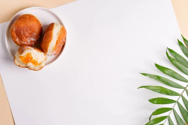 Donuts caseros horneados en un plato de cerámica blanca con hojas de palma sobre un fondo gris claro. Puesta plana . —  Fotos de Stock