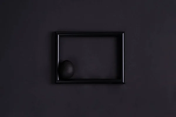 Œuf de Pâques noir par paintbrash de couleur noire sur le cadre photo noir et fond noir . — Photo