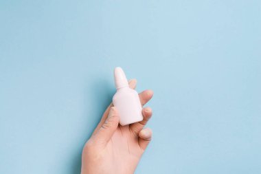 Tıbbi eldivenli kadın elleri açık mavi arka planda ampul tutuyor..