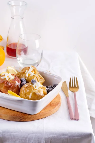 Jabłka pieczone z jagodami i serem wiejskim w misce z sztućcami na białym stole — Zdjęcie stockowe