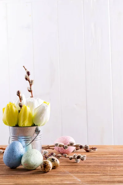 Buona Pasqua con tulipani freschi di primavera fiori in un secchio e uova dipinte a mano su un tavolo di legno . — Foto Stock