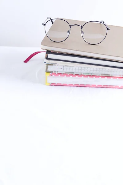 Pilha de livros de notas para notas e anotações com óculos no topo em uma mesa branca . — Fotografia de Stock