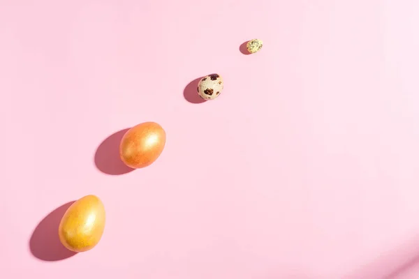 Tarjeta de vacaciones de Pascua con sombras, pollo pintado de oro y huevos de codorniz sobre un fondo rosa pastel . —  Fotos de Stock