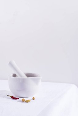 Beyaz porselen havan ve kırmızı biber ve kakule kaplı kabuk tekstil masasında izole edilmiş, boşluğu kopyala