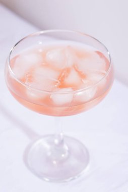 Masadaki beyaz masa örtüsünde buzlu pembe kokteyl.