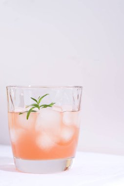 Biberiyeli pembe kokteyl ve masada beyaz bir masa örtüsü üzerinde buzlu cam.