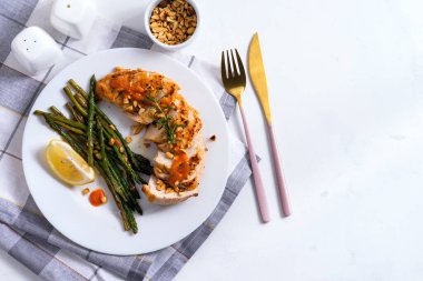 Izgara tavuk göğsü, ızgara kuşkonmaz ve limon dilimi, arka planda taş bir peçete. Paleo diyeti.