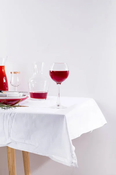 Rotwein im Weinglas, Dekanter und Tischdekoration mit Schatten auf weißem Textilhintergrund — Stockfoto