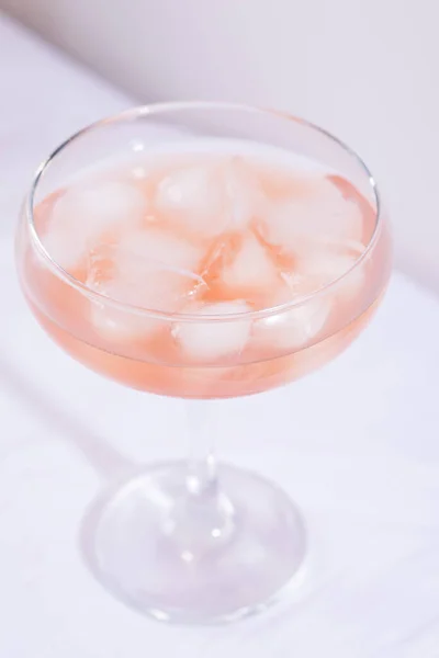 Cóctel rosa con hielo sobre un mantel blanco sobre la mesa —  Fotos de Stock