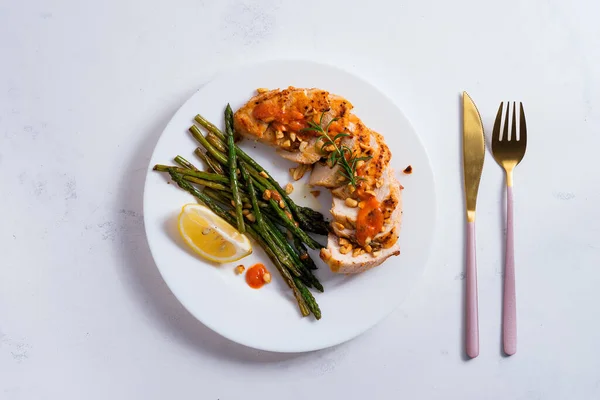 Grilled chicken breast with grilled asparagus and lemon slice on stone background . Paleo diet. — Stock Photo, Image