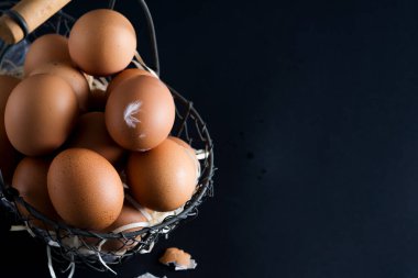 Siyah arka planda taze çiftlik yumurtalarının olduğu sepet. Çiftlik çevre dostu