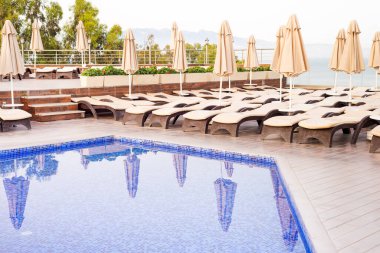 Güzel deniz manzaralı ve sisli dağları olan bir tatil köyünde yüzme havuzu ve mavi su manzarası