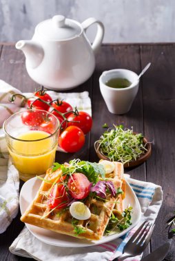 Lezzetli waffle, haşlanmış yumurta, domates ve açık arkaplanda mikroyeşil ile kahvaltı servisi yaptım. Aperatifler, aperatifler, brunch. Lezzetli sağlıklı yiyecek konsepti.