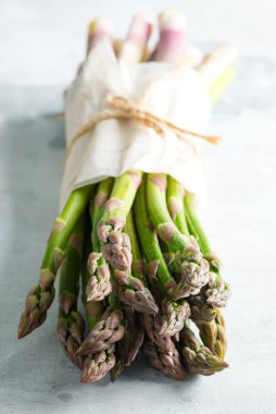 Dikey ayakta duran taze organik yeşil kuşkonmaz taştan arka planda yetişiyor..