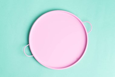 Açık turkuaz arka planda taze pişmiş gıdayı temsil eden boş pembe seramik tabak..