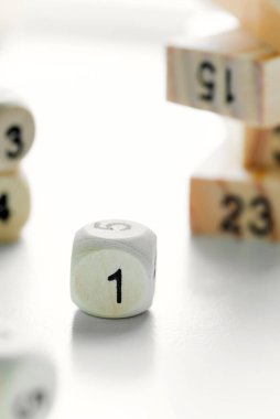 Açık gri arkaplanda tahta zar küpünün yüzünde bir numara. Bloklardaki bulanık piramyd Jenga oyunundan..