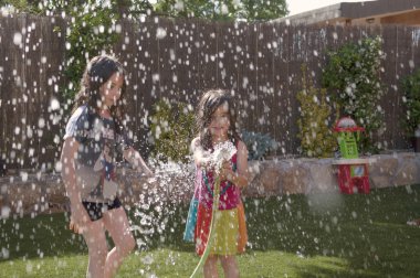 Bahçedeki hortumla ıslak oynayan kız