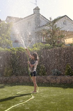 Bahçedeki hortumla ıslak oynayan kız