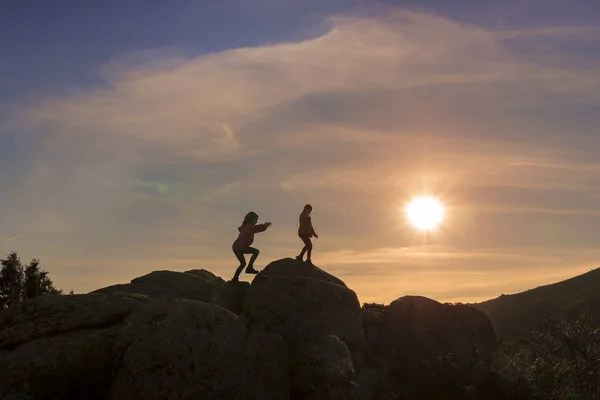 Девушки играют на закате на вершине горы — стоковое фото