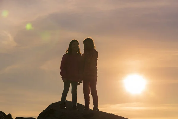 Flickor leker vid solnedgången på toppen av berget — Stockfoto