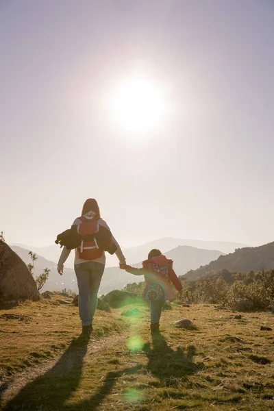 Mom keeps daughter\'s hand and walks on the nature in sunset ligh