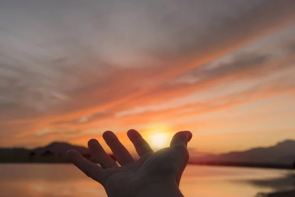 Pegando o sol com a mão no lago ao pôr do sol — Fotografia de Stock
