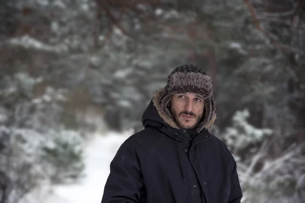 Giovane in abiti caldi e cappello a piedi nella foresta invernale — Foto Stock