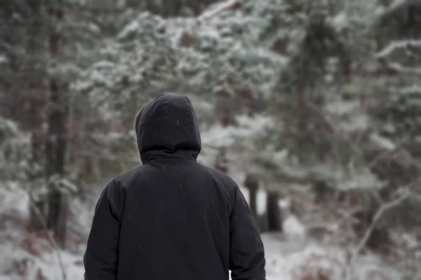 Hombre joven en ropa de abrigo y sombrero caminando en el bosque de invierno —  Fotos de Stock