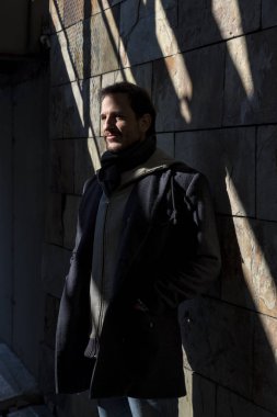 Genç adam gölgede güneşin ışınları tarafından aydınlatılmış pozlar