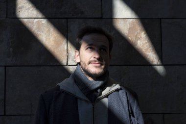 Genç adam gölgede güneşin ışınları tarafından aydınlatılmış pozlar