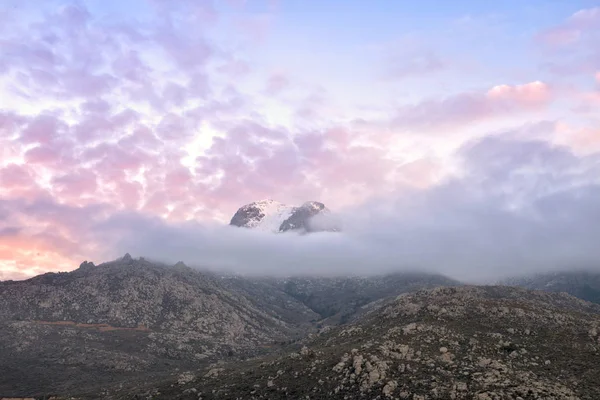 Auringonlasku savuisten pilvien yllä vuori — kuvapankkivalokuva
