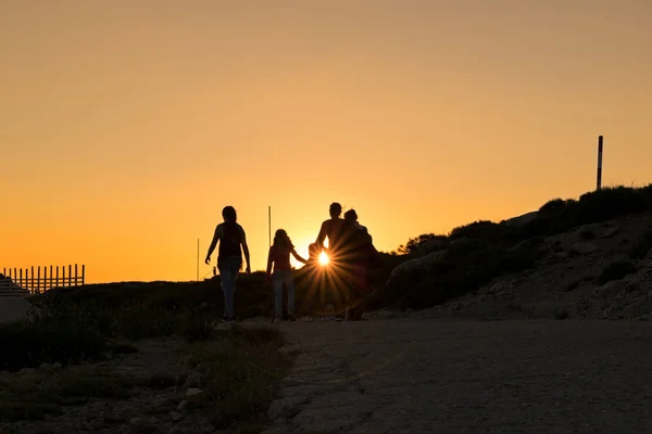 Silhuetas de caminhantes desfrutando de vista do pôr do sol a partir do topo de uma montanha — Fotografia de Stock