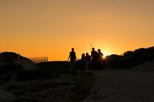 Silhouetten von Wanderern genießen die Aussicht auf den Sonnenuntergang vom Gipfel eines Berges — Stockfoto